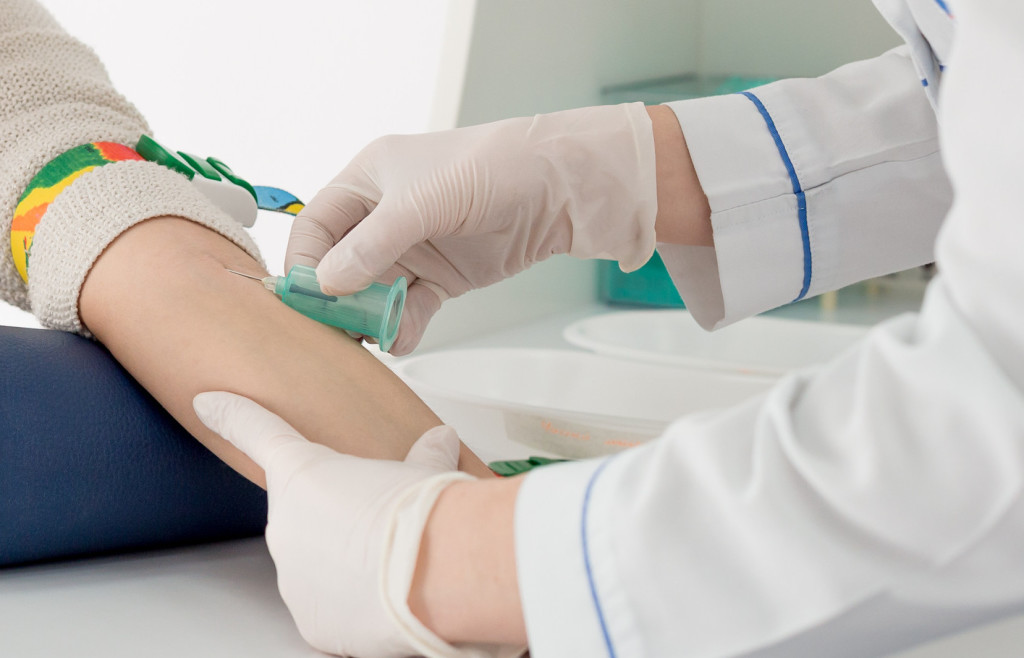 Gloved hands preparing a blood draw.