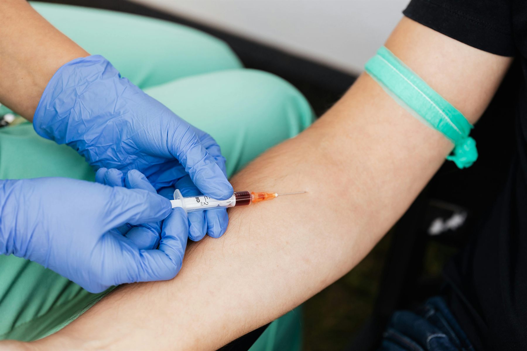 Close-up of a professional blood draw with blue gloves.